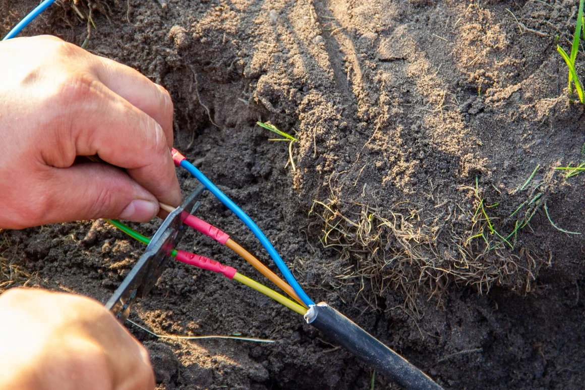 Person verbindet Kabel mit einer Zange.